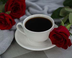 Cup of black coffe and red roses on grey background