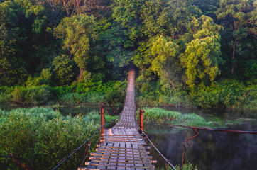 Wooden suspension bridge at sunrise over the Desna River near the town of Seltso