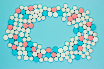 Frame made of white. blue and pink pills on color background, flat lay with space for text