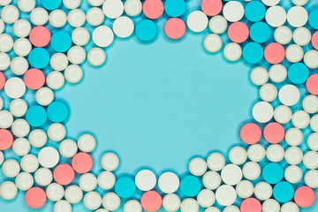 Round frame of white, blue and red pills on light blue background