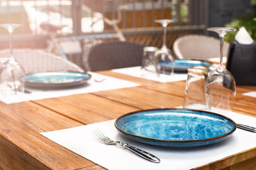 Breakfast table on the sun terrace. Blue plate on the table, waiting for visitors in the restaurant.