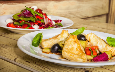 two dishes with salads of fried chicken, olives, basil, red pepper and lettuce, red cabbage, mozzarella, strawberry