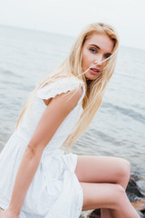 attractive blonde young woman in white dress looking at camera
