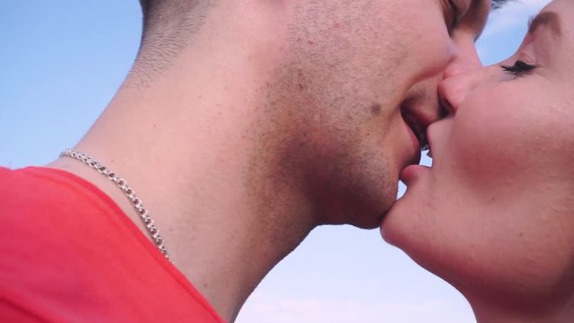 close up, young boy and girl kiss gently against the sky