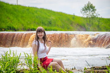 The girl at the waterfall. Young beautiful girl on a little waterfall. Little waterfall.