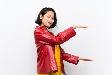 Asian young woman over isolated white background holding copyspace to insert an ad