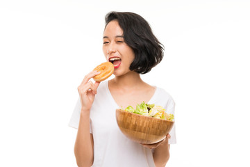 Asian young woman over isolated background with salad and donut