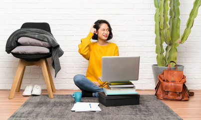 Asian young woman sitting on the floor having doubts and with confuse face expression