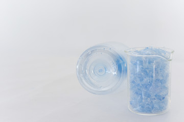 Bottle flake,PET bottle flake,Plastic bottle crushed,Small pieces of cut blue plastic bottles in beaker glass&Bottom of translucent bottle .Chemical concept
