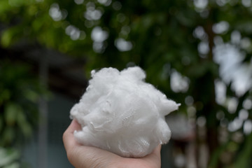 Hands holding polyester fiber with green blurred background.save environment concept
