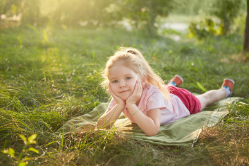 Fototapeta premium Little girl is lying on the grass