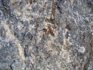 Background of granite rock. Dark stone with a layered structure. Light streaks and inclusions.