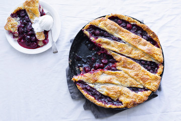 Cherry pie with a lattice and flaky crust shot on a white fabric