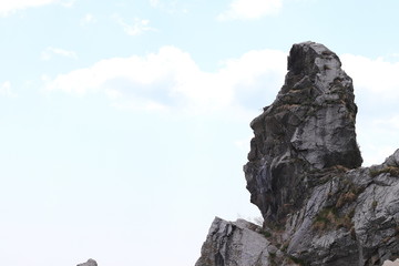 Rock looking like a human head on cloudy sky background with empty space for you text. For design of posters, presentations and post cards.