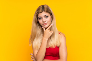 Teenager girl over isolated yellow background thinking an idea