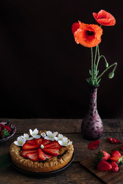 Strawberry tart with poppy flowers on wooden table