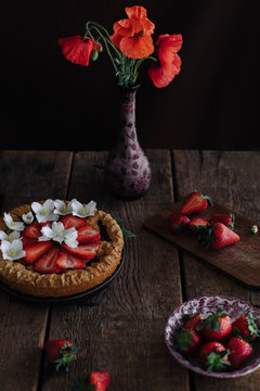 Strawberry tart with poppy flowers on a wooden table