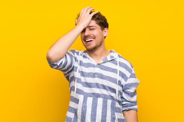 Blonde man over yellow wall has just realized something and has intending the solution