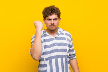 Fototapeta premium Blonde man over yellow wall with angry gesture