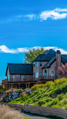 Vertical frame Home on a hill with lush foliage overlooking mountain and sky on a sunny day