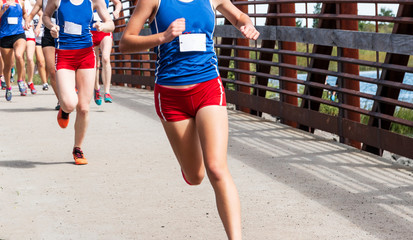 Cross country girls racing over a bridge at Sunken Meadow State PArk