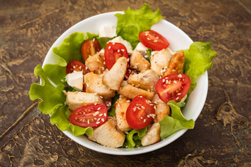 Salad with juicy chicken, tomatoes and soft cheese cheese. dressing with olive oil and sesame seeds. Top view