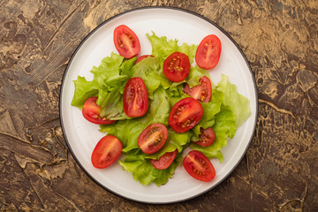 plate of salad with cherry tomatoes and lettuce. dressing with olive oil. Dietary food. Top view