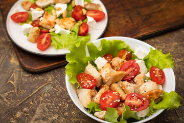 Salads with chicken, tomatoes and soft cheese. dressing with olive oil and sesame seeds. Diet food