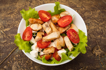 Salad with chicken, cherry tomatoes and soft cheese cheese. dressing with olive oil. Top view