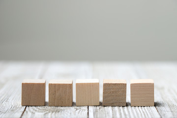 Five wooden toy cubes arranged in row on white grey wooden background