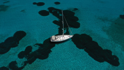 Aerial photo of sail boat docked in famous beach of Ornos, Mykonos island, Cyclades, Greece