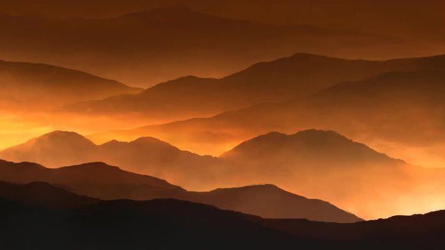 Fire Mountain Mist 4K Loop features mountain ranges with a golden glow and mist flowing between the ranges in a loop.