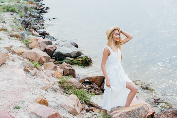 happy and beautiful blonde woman smiling while standing near sea
