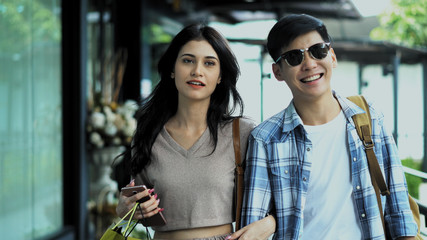 Young couple holding shopping bag and walking on walkway
