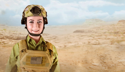 Portrait of young smiling US soldier woman in military uniform on desert background with space for text.