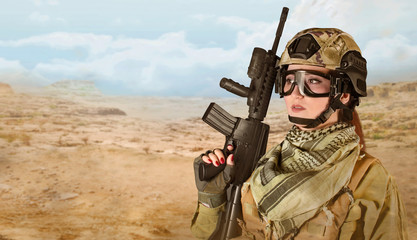 Fully equipped military soldier woman with red lacquer nails holding an automatic rifle M16 on desert background with space for text.