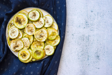 Baked zucchini cut in circle pieces. On plate. Top above view. Vegan and vegetarian food. Healthy diet. Space for text
