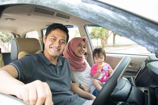 Young Muslim Family , Transport, Leisure, Road Trip And People Concept - Happy Man, Woman And Little Girl Traveling In A Car Looking Out Windows At Sunny Day