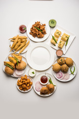 Indian Tea time snacks  in group includes Veg Samosa, Kachori/kachaudi, aloo bonda, khaman dhokla, bread, onion,chilli and moong pakora/pakoda/bhaji/bhajji/Bhajiya/bajji with sauces, selective focus