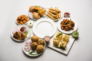 Indian Tea time snacks  in group includes Veg Samosa, Kachori/kachaudi, aloo bonda, khaman dhokla, bread, onion,chilli and moong pakora/pakoda/bhaji/bhajji/Bhajiya/bajji with sauces, selective focus
