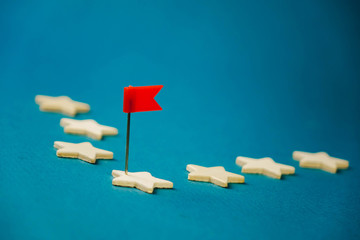 wooden cubes in the form of stars lined up in a chain and one star with a red flag, the star with...