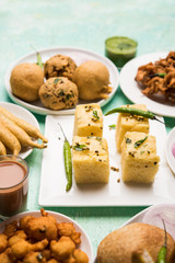 Indian Tea time snacks  in group includes Veg Samosa, Kachori/kachaudi, aloo bonda, khaman dhokla, bread, onion,chilli and moong pakora/pakoda/bhaji/bhajji/Bhajiya/bajji with sauces, selective focus