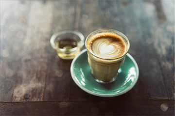 Coffee cup latte art with green saucer on wood background