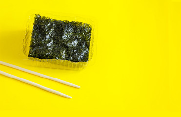 Dry korean organic seaweed isolated on yellow  background. Dried nori seaweed laminaria sheet, Healthy food concept.
