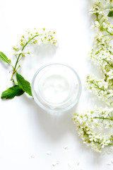 Obraz na płótnie Canvas Jar with cream and flowers on white background. Beauty blogger flat lay concept.Woman's skincare routine. Daily face cream.Place for your text or logo.