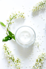 Jar with cream and flowers on white background.  Beauty blogger flat lay concept.Woman's skincare routine. Daily  face cream.Place for your text or logo.