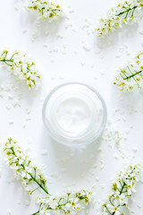 Fototapeta na wymiar Daily face cream. Jar with cream and flowers on white background. Woman's skincare routine. Beauty blogger flat lay concept.Place for your text or logo.