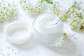 Dermatology cosmetic hygienic cream with white flowers skincare product-top view. Moisturizing face cream for spa treatment. Beauty background with facial cosmetic product. flat lay. 