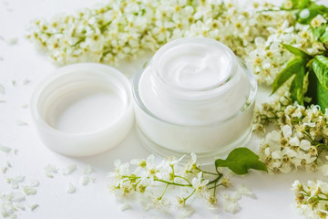 Fototapeta na wymiar White Face Cream. Dermatology cosmetic hygienic cream with white flowers skincare product. Moisturizing face cream for spa treatment. Beauty background with facial cosmetic product. flat lay. 
