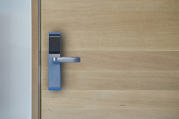 Digital door knob or electronic door handle on wooden door. Selective focus.